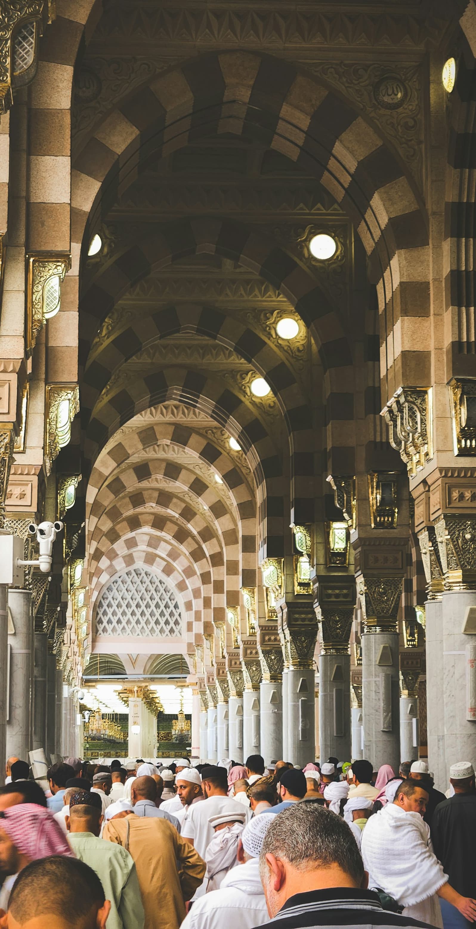 Pilgrims walking through the arched corridor of Al Masjid an Nabawi